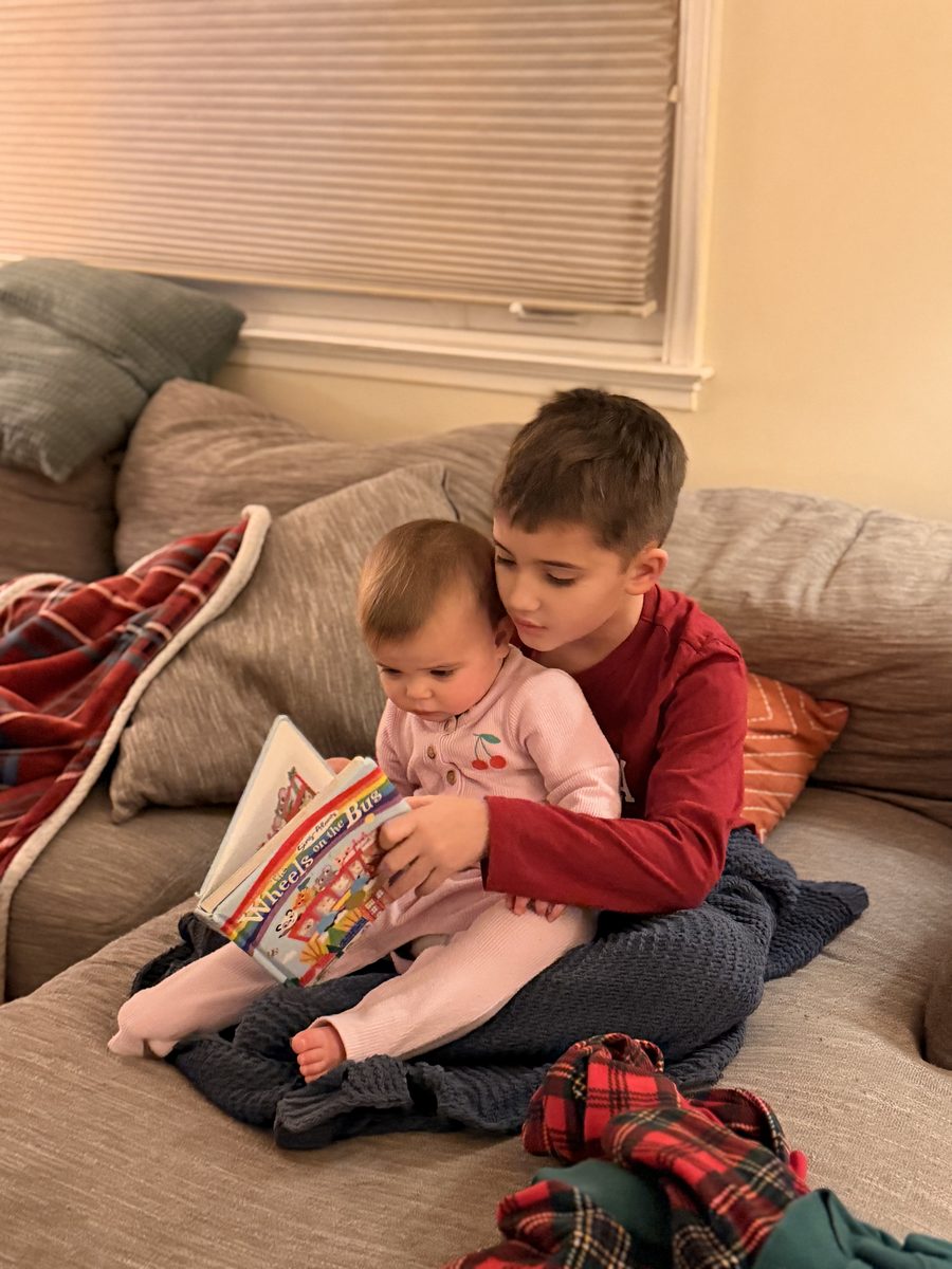 Oliver reading to his little sibling — a reader from day one